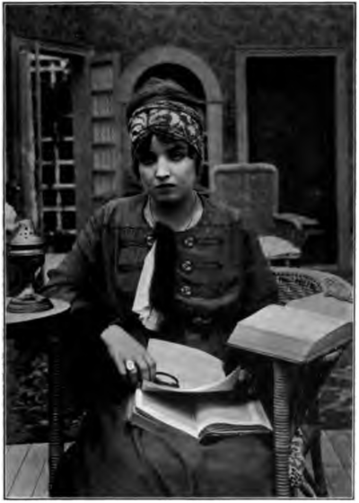 Madelyn Mack, sitting with books and a magnifying glass.